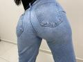 OliviaGranda's ass in tight blue denim jeans, showing two pockets, with a slightly worn texture and a black top visible at the top of the frame.