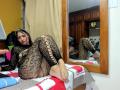 AfroditaHan with dark hair, wearing a black lace bodysuit, lying on a bed with her ass up, feet on the bed, reflection in a wooden-framed mirror.