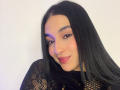 EmmaWaltter with long black hair, wearing a black mesh top, has a cute smile, pink lipstick, and subtle purple eye makeup. She's looking at the camera with a slight tilt.
