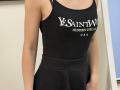 Rorria's black tank top and skirt, showing her small boobs and slim arms, with text on the top, in a simple indoor setting.