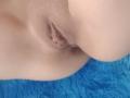 A vulva de SharonKm, mostrando seus lábios e vagina em um close-up. Ela tem pele clara e está posicionada em uma superfície azul e peluda..