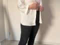 Elliance's white shirt is open, revealing her small tits in a striped bra. She's wearing black pants, standing in a room with a white door in the background.