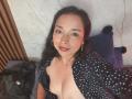 StangelarRivera is lying down with legs up, wearing black polka dot top and black straps on her thighs. She has long dark hair, hoop earrings, and a slight smile.