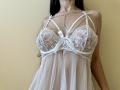 Tisia's white lace babydoll shows her tits with intricate patterns, sheer fabric, and ribbon accents. She's wearing a delicate necklace, and her long dark hair is visible.