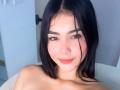 NahomiMillerr with black hair, fair skin, brown eyes, and a slight smile, showing her bare shoulders, has a cute nose ring and subtle makeup.