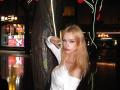 DalliaBanowski with long blonde hair, white off-shoulder top, leaning on a tree, night setting, reflective floor, small nose, pouty lips, slim figure, looking at camera.