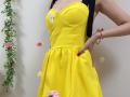 MiraMixi's yellow dress has a cute, floral pattern with pink and white flowers. She's got a black strap, red nail polish, and a bracelet on her right hand.