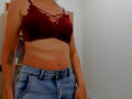 Steisii with tan lines, wearing a red lace bra, showing her small tits, and blue denim jeans, has a tattoo on her left arm.