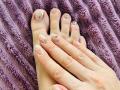 MikyWayxy's feet with nude polish, glitter on toes, and fingers resting on a purple, textured blanket. Hands and feet are slightly overlapping.