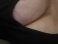 Barbarica's big, pale, hairy tits are visible in a black top, showing a slight tan line and visible veins. The image focuses on her chest from the side.