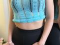 Stefanni's blue lace crop top showing her tits, black high-waisted pants, and a slim waist with a visible navel, standing with her right hand on her butt.
