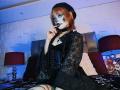 ViolettClay, goth chick with white face paint, black lace robe, corset, and beret, sucks finger, sitting on bed, red lamps, dark room, pale skin, orange hair, small tits.
