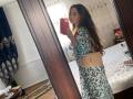 JaneKrover with long brown hair, wearing a blue floral dress, holding a red phone, and a beige quilted purse with a gold logo, showing her ass in a mirror selfie.