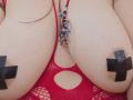 SultanaLm's big boobs in a red mesh top, with black X-shaped pasties covering her nipples, and a beaded necklace hanging between her tits.