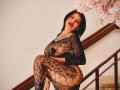 DonnaJones in a black lace outfit with large circular cutouts, exposing her big tits and thick ass, squatting on a staircase with cherry blossoms in the background.