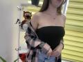 Nesie with bare shoulders, black strapless top, denim jeans, pink and black plaid shirt, necklace, long brown hair, tiger stuffed animal, butterflies on shelf, yellow blinds.