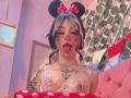LaurenEvie69 with black and white hair, Minnie Mouse ears, face paint, tongue out, transparent lace top, tattoos, and a red polka dot cloth. Pink room, plant wall.