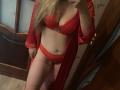 CharlineGusty in red lingerie, showing her tits in a bra and matching panties, with a red robe, holding a phone to take a mirror selfie. Her blonde hair is down.