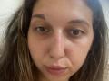 Sanella's face, showing a slightly sweaty forehead with brown eyes, subtle eyebrows, and light brown, wavy hair, in a neutral expression. Her nose is centered, with small pink lips.