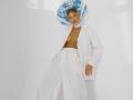 EolantaMarina with blonde hair, wearing a white jacket, white pants, and a blue floral headscarf, topless, exposing small tits, against a white wall, looking down.