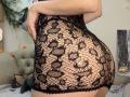 SugarrX's ass in a black, lace, see-through dress with circular patterns, showing her bare skin and curves. She's standing with her back to the camera.