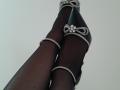 AmeliaMaiv's legs in black sheer stockings, wearing sparkly high heels with bows and diamonds, crossed at the ankles, showing off her sexy, dark-skinned, shapely feet.