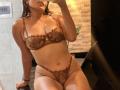 AmeliRoux in brown lace lingerie, showing her tits and pussy, taking a mirror selfie, smiling, with long dark hair, tan skin, and a black wristband.
