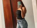 AntoniaBrunni with long red hair, wearing a black strapless top and high-waisted blue jeans, taking a mirror selfie with a green phone, showing her ass and slim waist.