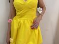 MiraMixi wearing a bright yellow dress with a V-neck, showcasing her tits in a fitted top, red nails, a ring, and pink and white flowers on a string.
