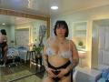 ViviWollds with black bob, white lace bra, and black panties, tattooed, holding her black panties, showing her tits, ass, and pussy, in a modern, mirrored bedroom.