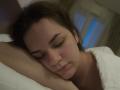 Dreia's sleepy face, eyes closed, brown hair, white pillow, arms folded, soft expression, slight smile, wearing a white shirt, dim bedroom light, gentle blue glow in background.