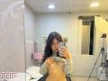 ValeryBeaumont is taking a mirror selfie, lifting her gray sweater to expose her small, perky tits. She has long, wavy brown hair and is wearing red lipstick.