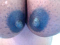 Close-up of SweetBellaG's large, round breasts with dark blue areolas and pronounced nipples. The skin has a speckled texture. The image is highly detailed and sexual in nature.