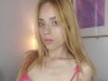 LyannaDifran with blonde hair, pink lace bra, pink eye makeup, light skin, pouty lips, and a slight smile, looking at the camera. Her tits are small and she's cute.