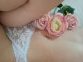 AmeliaMaiv's bare lower belly with white lace panties, pink roses on her skin, and her soft, curvy, pale body in the frame. Her navel is visible.
