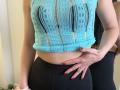 Stefanni's blue lace crop top shows her boobs with a black bra underneath. She's wearing black pants, hand on her ass, red nails, and a white bracelet.