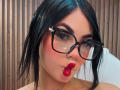 EllieeSmith has black hair, thick eyebrows, red lipstick, and wears black glasses with a small star on the right side. She's making a pouty, slightly wet-looking face.