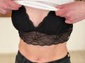 Sanella's black lace bra with a V-shaped neckline, showing her small tits, as she pulls up a white shirt, revealing a lace pattern across her chest.