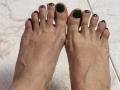 SarahRousen's toes have dark green painted toenails, showing her slightly wrinkled, pale skin and visible veins on her feet. Her toes are positioned side by side.