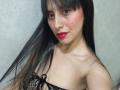 MadissonFontaine with long black hair, red lipstick, and black lace top, showing her small tits and a beauty mark on her right cheek. She's wearing a jeweled forehead piece.