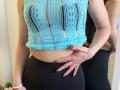 Stefanni's blue lace crop top with visible black bra, showing her tits, paired with black leggings. Her hand with red nails rests on her black ass. Reflection visible.