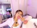 AlessiaFerry with brown hair, wearing a white top, sucking a pink dildo. Her tits are visible, and she's looking at the camera. Reflection in mirror shows her ass.