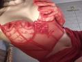 Rozalin wearing red lace lingerie with her hand covering her tits, sheer fabric, small red bow, and red gloves, showing her slim, fair-skinned, and curvy body.