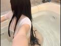 RoxanneeSecret in a bathtub, wearing a wet white shirt that's transparent, showing her big tits. She's got long black hair and is reaching out with her right arm.