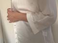 Elliance's hands clutching a white shirt, exposing buttoned chest. White shirt, loose sleeves, light skin. Elliance's fingers, slightly curled, with a simple ring. Soft, neutral lighting.