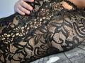 La tuta nera in pizzo di Dinastiia, con motivi floreali, mostra la sua pelle nuda e una mano appoggiata sulla pancia. La sua vulva è leggermente visibile attraverso il pizzo..