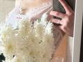 DominicaChambley's lace-covered tits in pink, holding a bouquet of white chrysanthemums and a smartphone with a ring on her finger, reflected in a mirror.