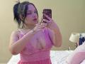 AlayaWillow with big tits in pink lace nightie, taking a selfie in a mirror, wearing pink eye makeup, ring on left hand, tattoos on right wrist and chest.