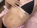 TenerliRize's flat stomach, black bikini top with pink trim, pink bikini bottoms, belly button piercing, tattoo under left breast, pale pink nails, silver ring, pink bracelet.