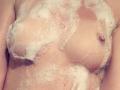 SarahFontain's tits covered in foamy soap suds, with bubbles clinging to her light skin and small, pink nipples, in a close-up shot of her upper body.